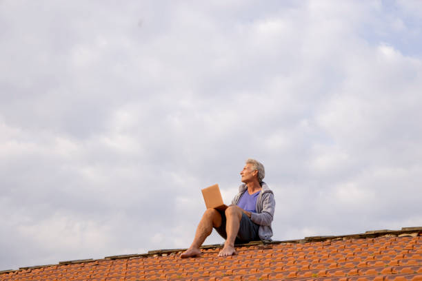 istock Senior man uses laptop on rooftop 1438440839