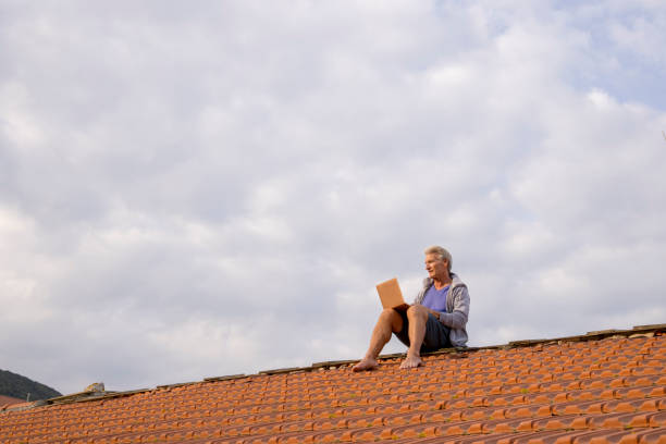 Senior man uses laptop on rooftop