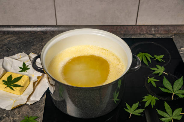 Cooking of marijuana butter in hot water on electric cooker in kitchen stock photo