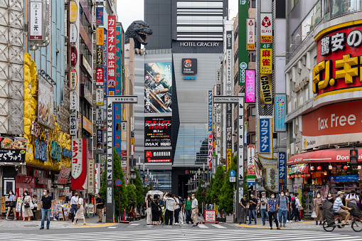 Tokyo, Japan - September 4, 2022 : People at Godzilla Road in Kabukicho, Shinjuku, Tokyo, Japan. At the end of the road a giant Godzilla head sitting atop a movie theatre.