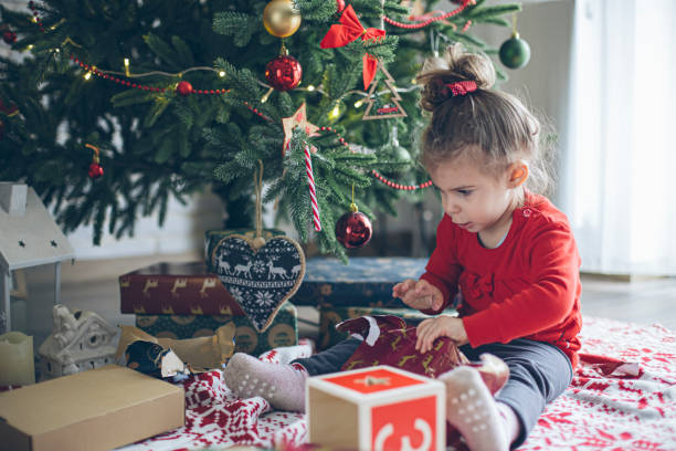 istock Cute little toddler opening present near Christmas tree 1438443186