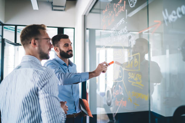 istock Intelligent financial experts analyzing report on glass board spending working time for communication during brainstorming indoors, young experienced colleagues briefing at executive information 1438443207