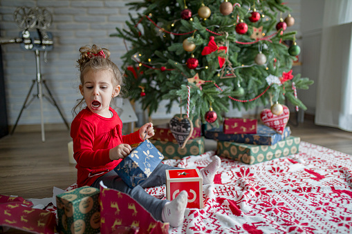 Cute little girl opens a gift on Christmas morning