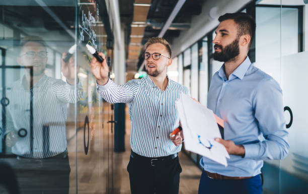 istock Smiling male employees discussing cooperation planning having productive job and conversation, 20s prosperous men employees talking about report and solutions on consultancy meeting in office 1438443819
