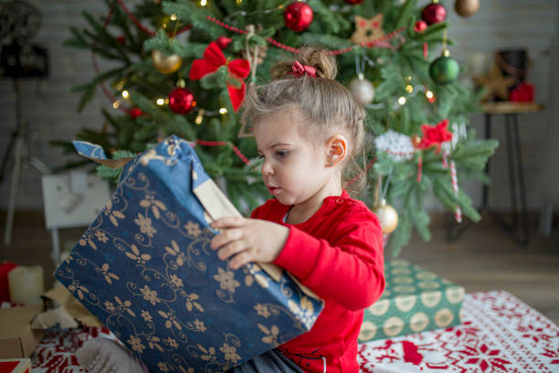 istock Surprised cute child girl opening a Christmas present 1438444002