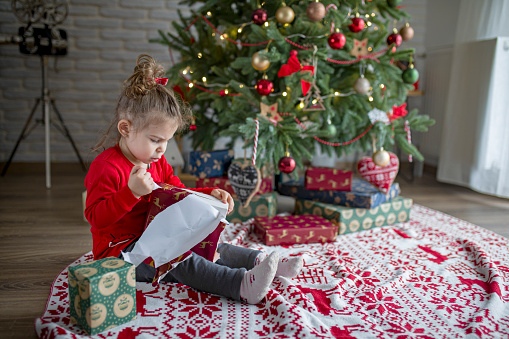 Surprised cute child girl opening a Christmas present