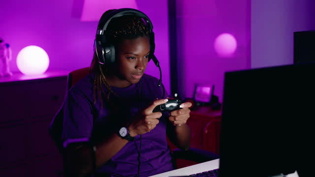 African american woman streamer playing video game using joystick at gaming room