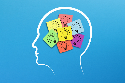 Notes with light bulbs inside human head on blue background