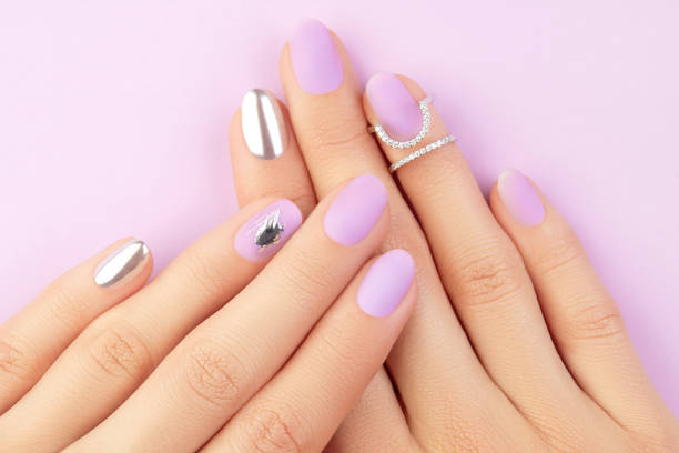 istock Close up womans hands with matte lavender and silver nails. Beauty treatment 1438445191