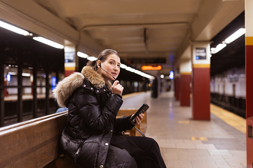 Female political at subway station, using smart phone