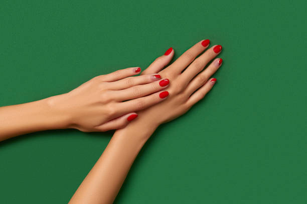 istock Womans hands with trendy christmas red manicure on green background 1438447021