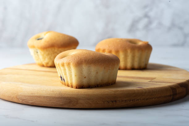 istock Three homemade cupcakes on a wooden cutting board. 1438448717