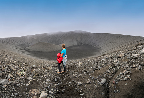 One women standing at the edge of the Hverfjall volcanic crater.  Hverfjall, is one of the best preserved circular volcanic craters in the world and it is possible to walk around and inside it.