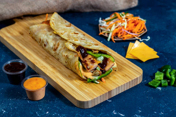 istock Egg Cheese Chicken Burger shawarma Wrap with salad dip and sauce isolated wooden board side view of fastfood 1438449094