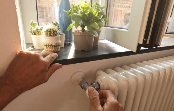 Detail of hand turning on radiator in house stock photo