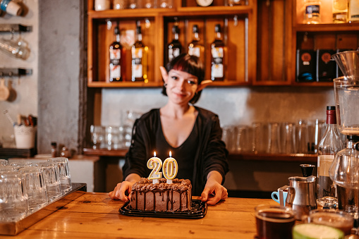 Young female barista celebrating birthday behind a bar counter.