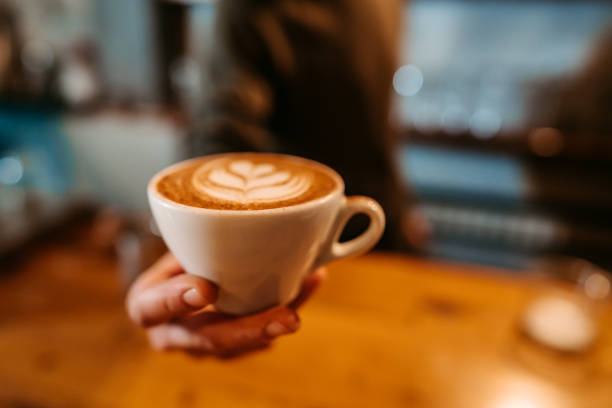 Close-up of a young barista serving a cup of coffee in a coffee shop.