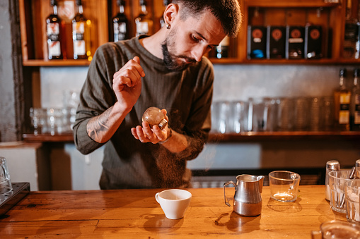 Close-up of a young barista making a cup of coffee in a coffee shop.
