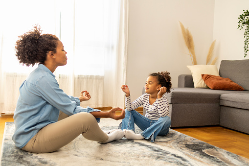 Mother and daughter practice meditation in the living room