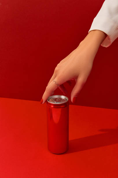 istock Manicured womans hand with soda can on a red background in sunlight 1438455471