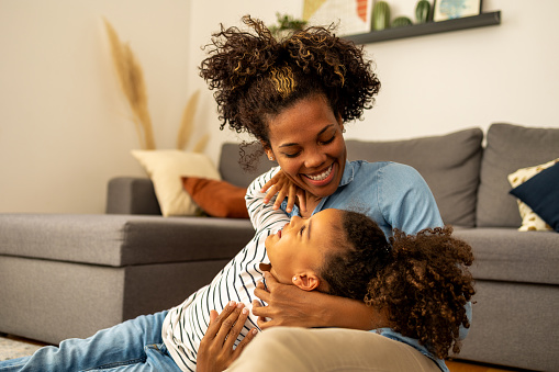 Mother and daughter sitting in the living room, they are having fun