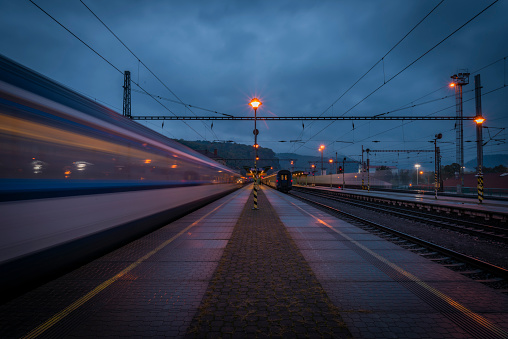 Decin station on platform in blue dark cloudy evening with trains