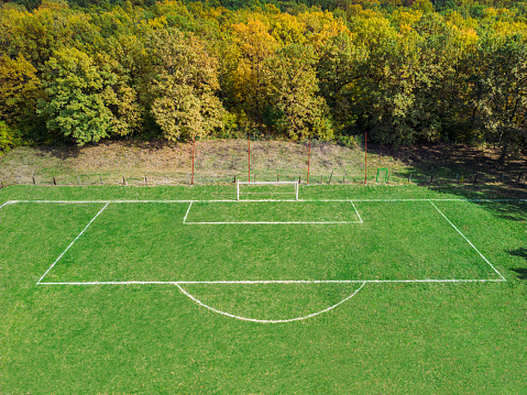 Aerial view of empty football field in middle of forest. Beautiful autumn day
