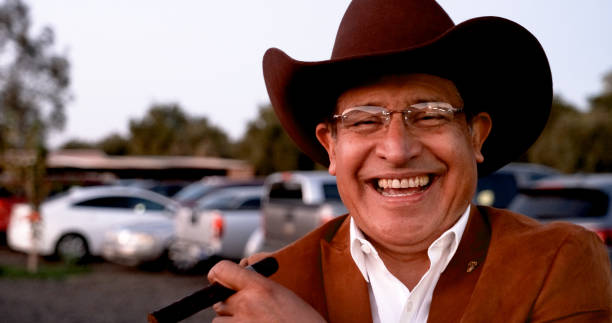 Smiling senior latino man wearing a cowboy hat looking at the camera