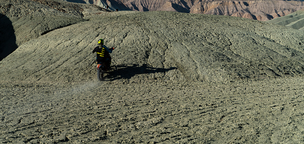 A speed race with cross bikes on an obstacle course on rough dirt terrain. 
The motor driver is climbing the hill over rough terrain. Shot with a full frame camera.