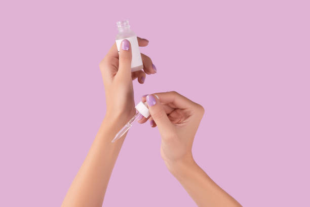 istock Womans hand holding dropper with serum on pastel lavender background 1438461837