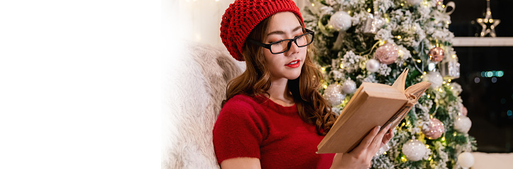 Portrait of nerd asian woman hold book in winter Christmas living room. Smile happy asian girl  knowledge education university woman asia winter lifestyle, back to school.