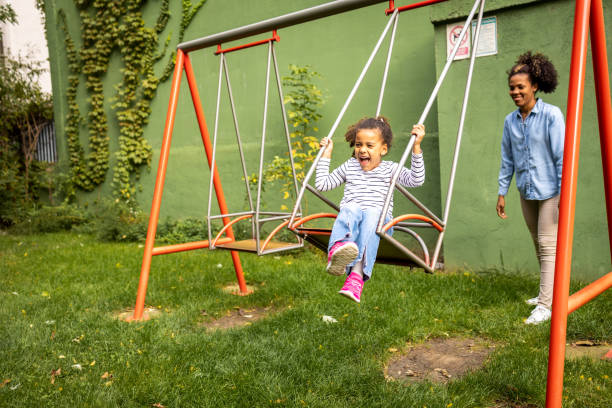 Happy mother having fun with your child on a swing stock photo