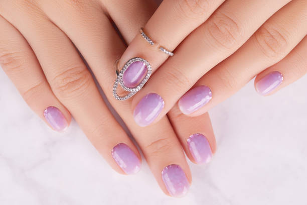 istock Womans hands with trendy lavender manicure. Spring summer nail design 1438462435