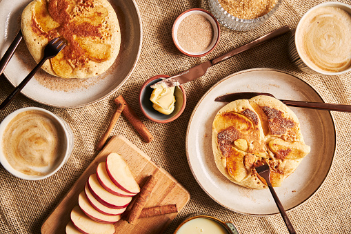 An overhead shot of apple pancakes coffee apples and other ingredients on a table