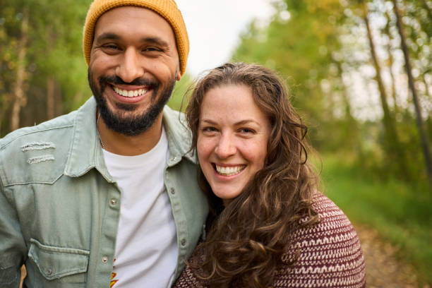 Laughing young couple standing on a country road Portrait of a young couple laughing while standing together on a tree-lined country road at sunset 30 39 years stock pictures, royalty-free photos & images