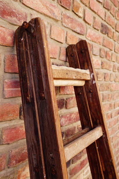 istock Vertical shot of a wooden foldable ladder leaned against a brick wall 1438466350