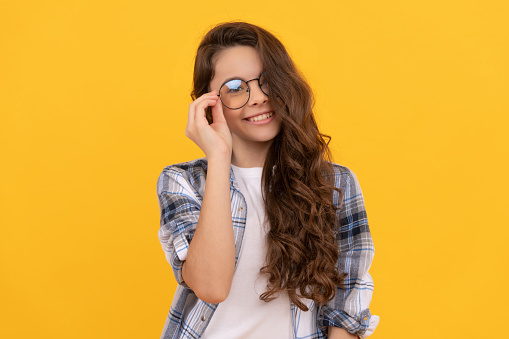 glad teen child in checkered shirt and glasses on yellow background.