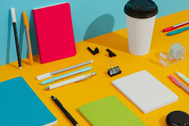 istock Colorful notepads, pens and paper cup on orange table 1438467938