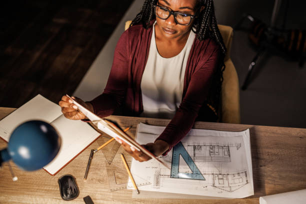 istock Female architect working on a project at her desk late at night 1438468096