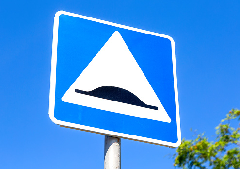 Triangle speed bump road sign against the blue sky. Warning traffic sign Speed bump