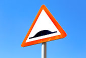 Triangle speed bump road sign against the blue sky
