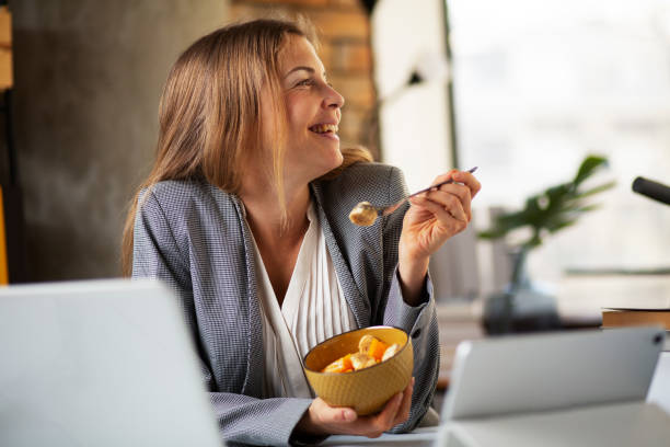 Young woman eating fruit while having a video call. stock photo