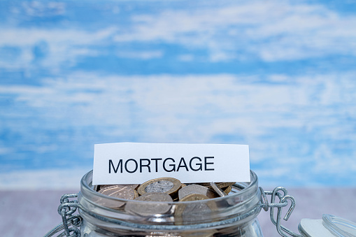 A paper label with the word Mortgage on top of a jar of coins