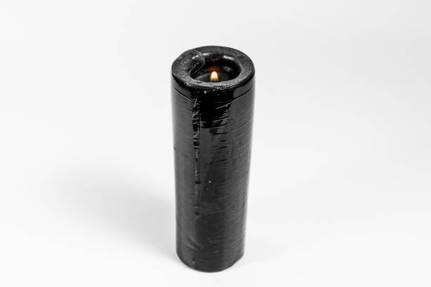 A tall black candle isolated on a white background
