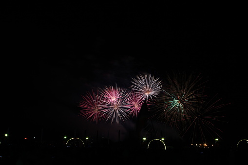 Multicolored fireworks in the dark sky, city day celebration