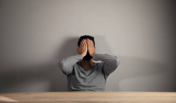 istock A man sits in front of a table covering his face with his hands 1438475241