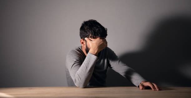 istock A man sits in front of a table covering his face with his hand 1438475249