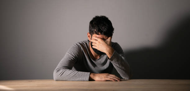 istock A man sits in front of a table covering his face with his hand 1438475251
