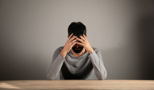 istock A man sits in front of a table covering his face with his hands 1438475253