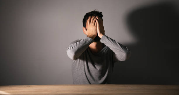 istock A man sits in front of a table covering his face with his hands 1438475260